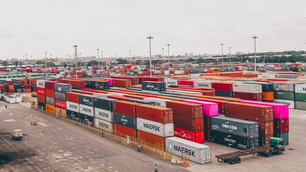 Contêineres coloridos empilhados em um movimentado porto de cargas.