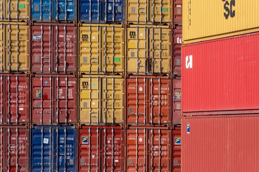 Contêineres coloridos empilhados em um porto, representando operações de transporte e comércio internacional.